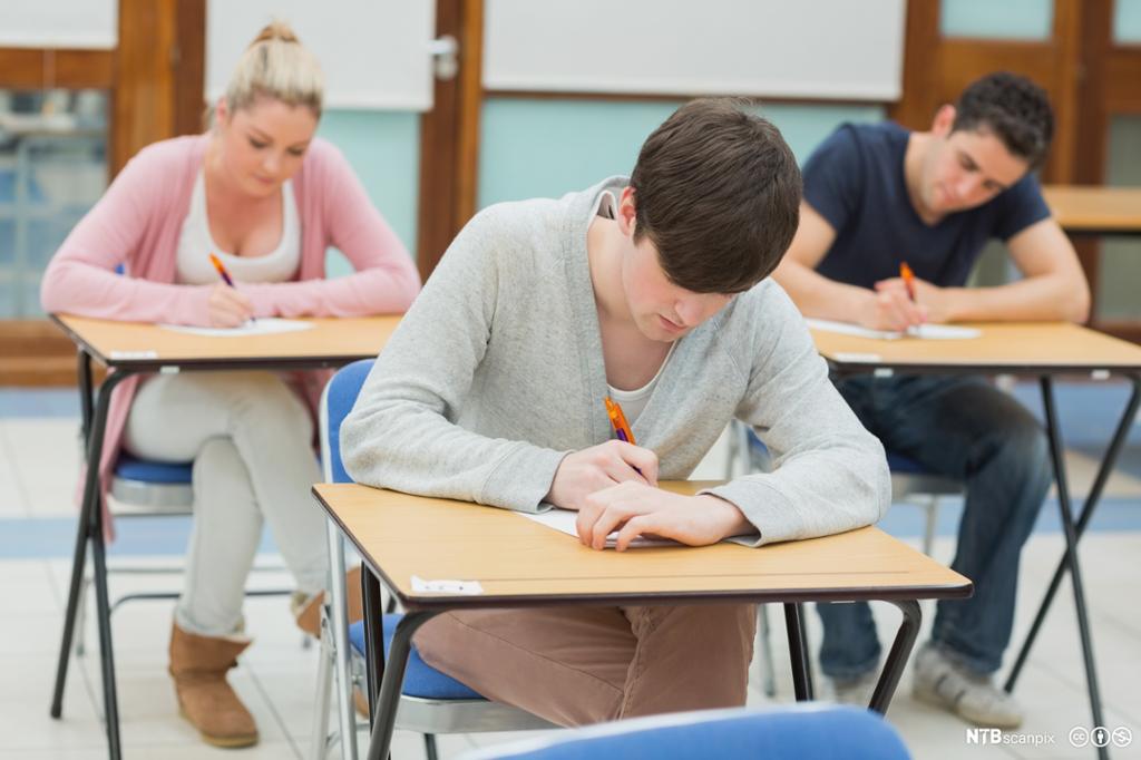 Elever som skriver i et klasserom. Foto.