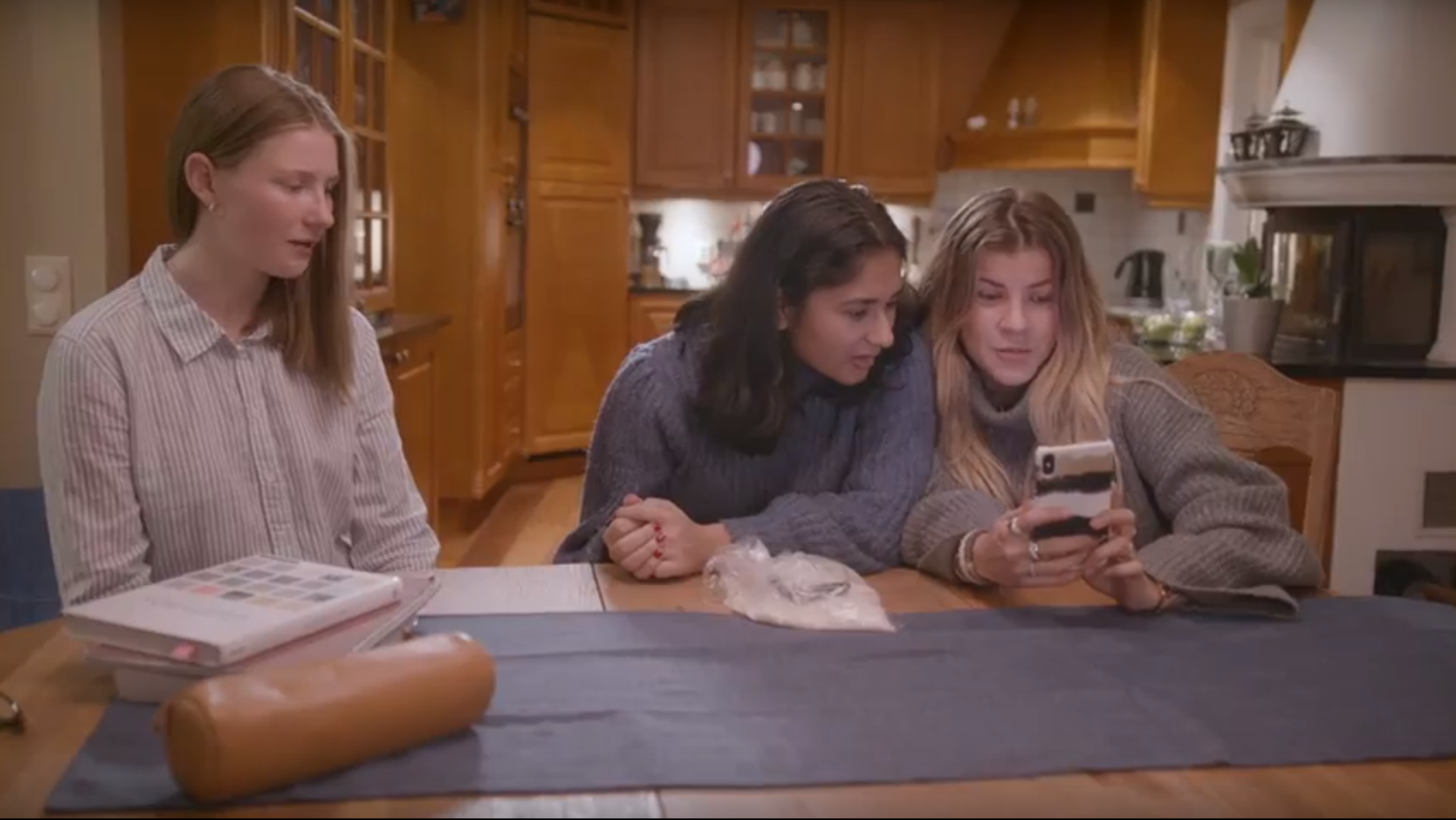 Tre jenter ser på samme mobil. Foto.