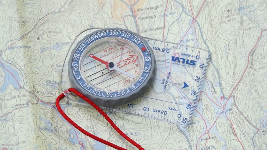 Kompass som ligg på eit kart. Foto.