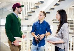 Tre studenter står og snakker med hverandre i en trapp. Foto.