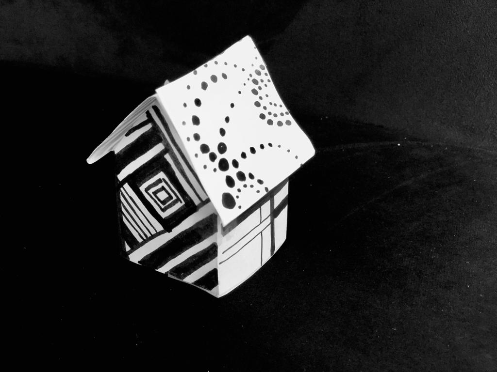 Fotografi av papirhus som er dekorert med svart tusj. 