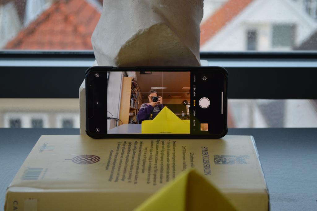 Bilde av en mobiltelefon plassert oppå en bok.