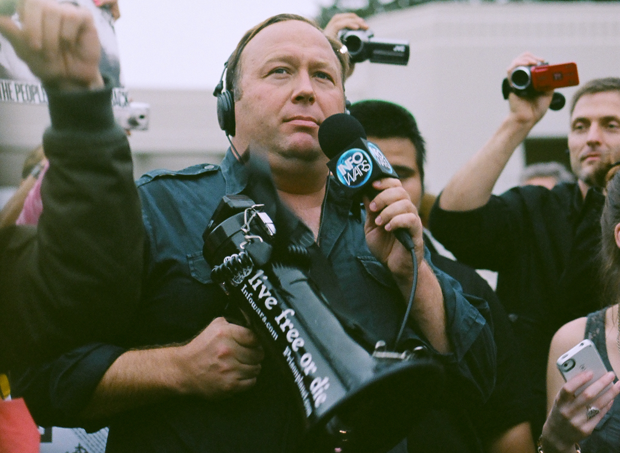 Mann med mikrofon og megafon. På megafonen står det "live free or die". Foto.