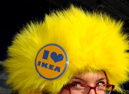 En IKEA-kunde har en stor og gul fluffy lue det står «Jeg hjerte IKEA» på. Foto.