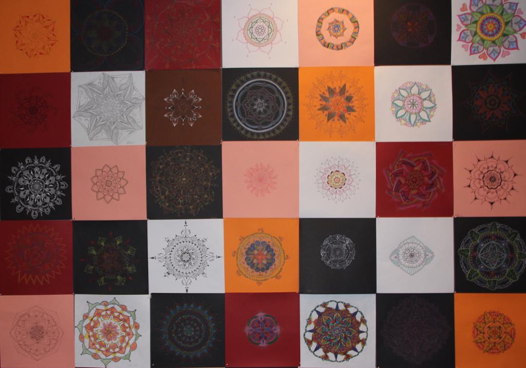 35 fargerike mandala-illustrasjoner uten avstand mellom dem er utstilt på en vegg . Foto.