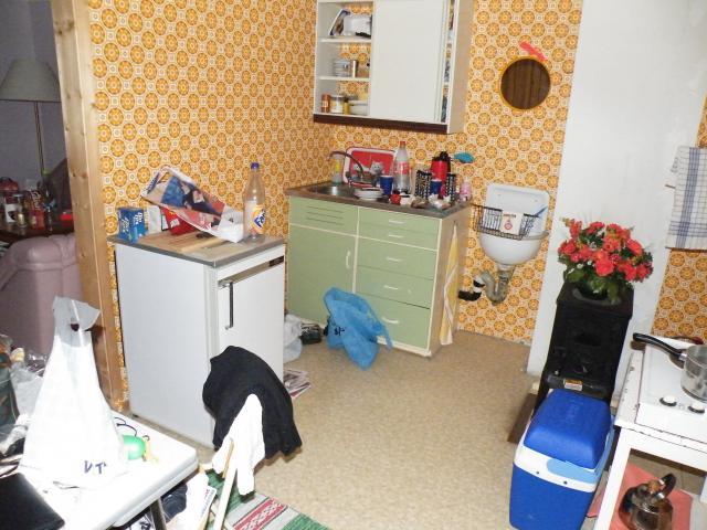 Kjøkken av eldre modell med ein del rot på kjøkkenbenk og golv. Foto.