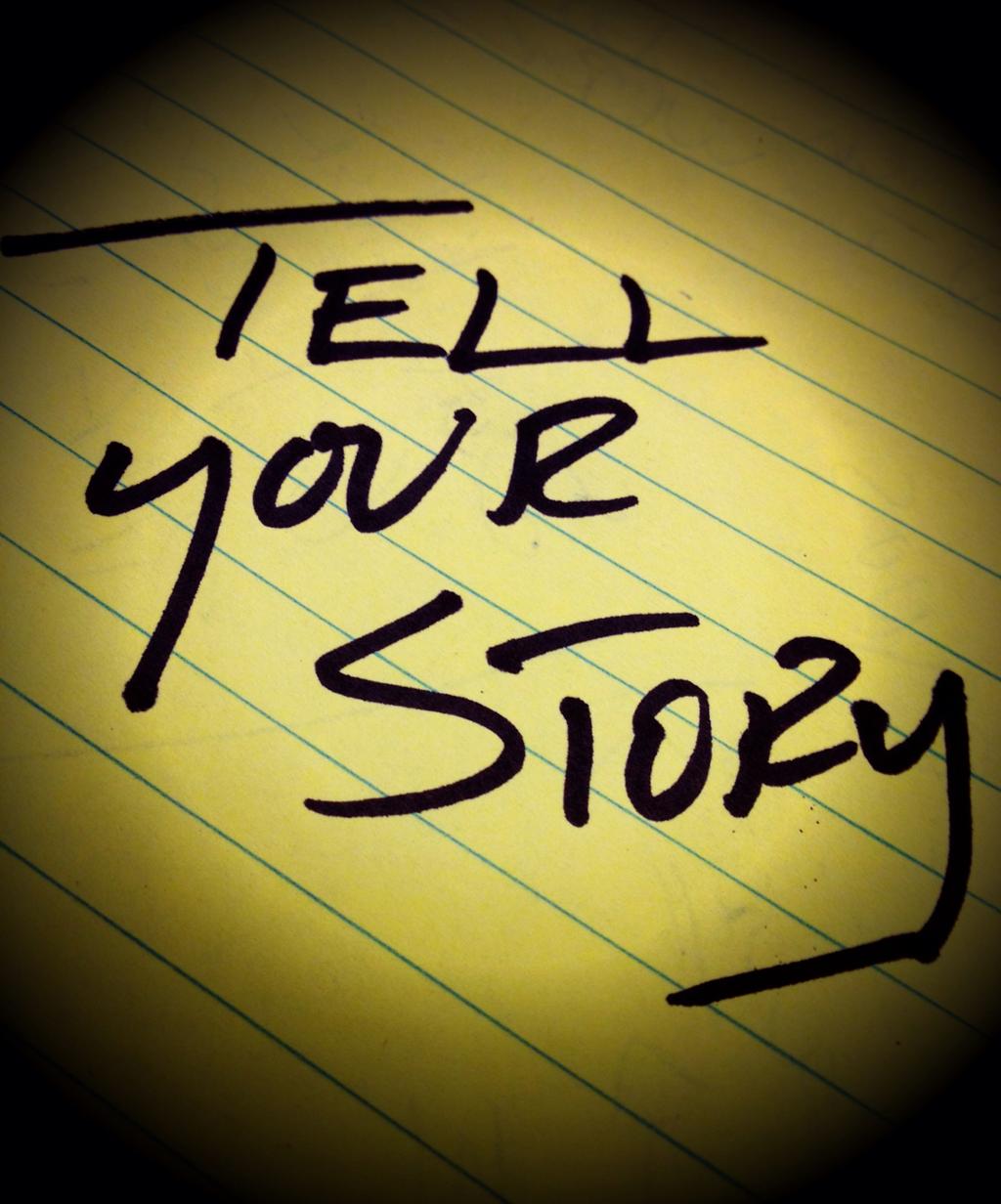 A hand-written note saying 'Tell your story' Black writing on yellow paper.  