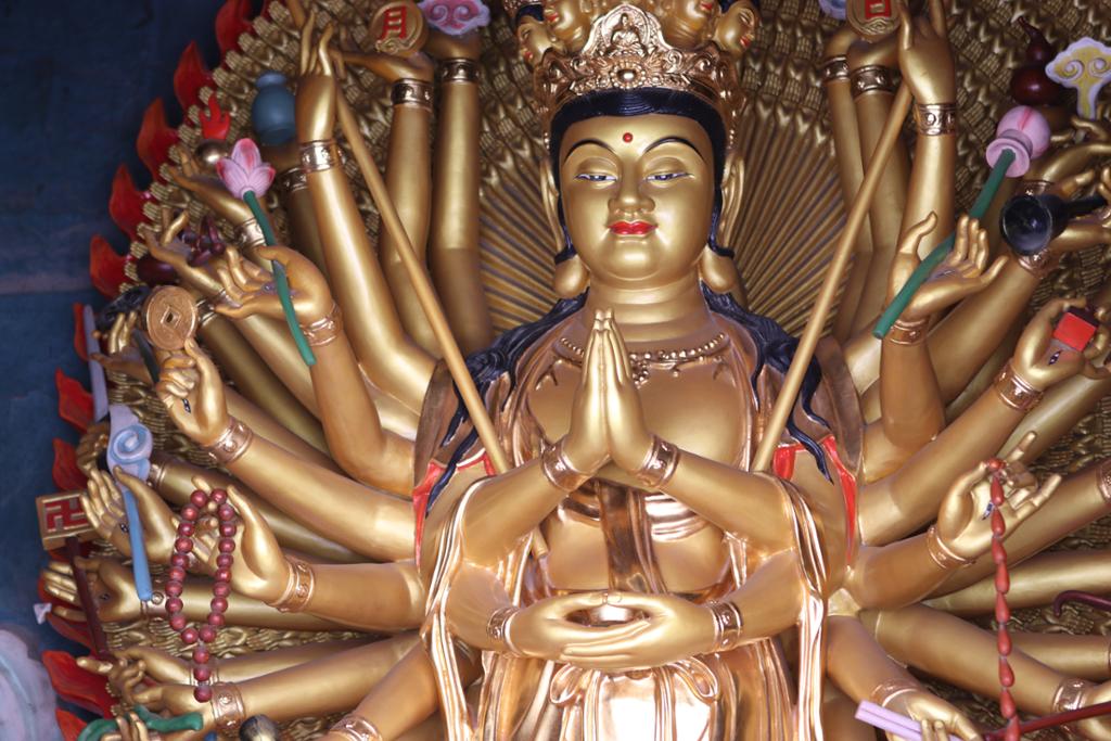 Buddhistisk statue med mange armer. Skulptur.