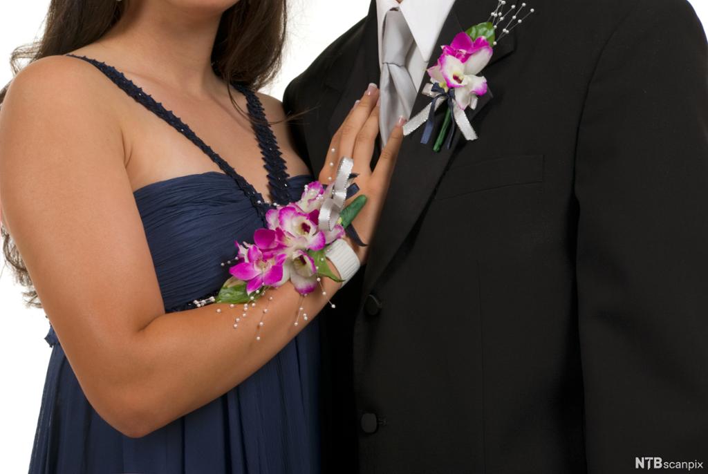 En dame har et blomstersmykke på armen, og en mann har et blomstersmykke på dresskragen. Foto.