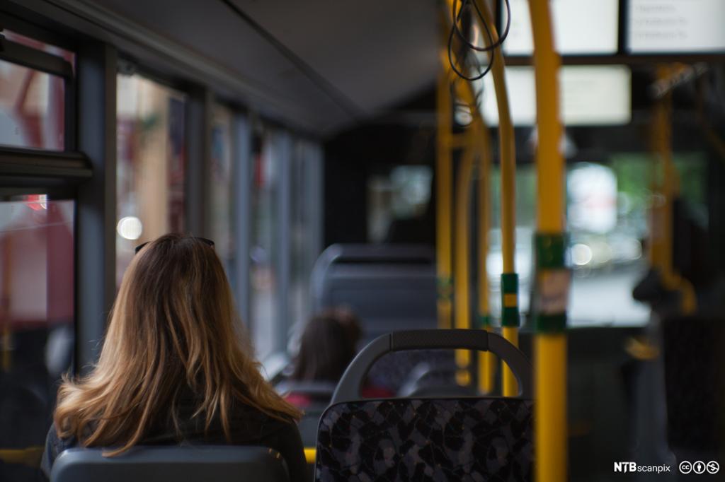 Jente sitter alene på buss. Foto.