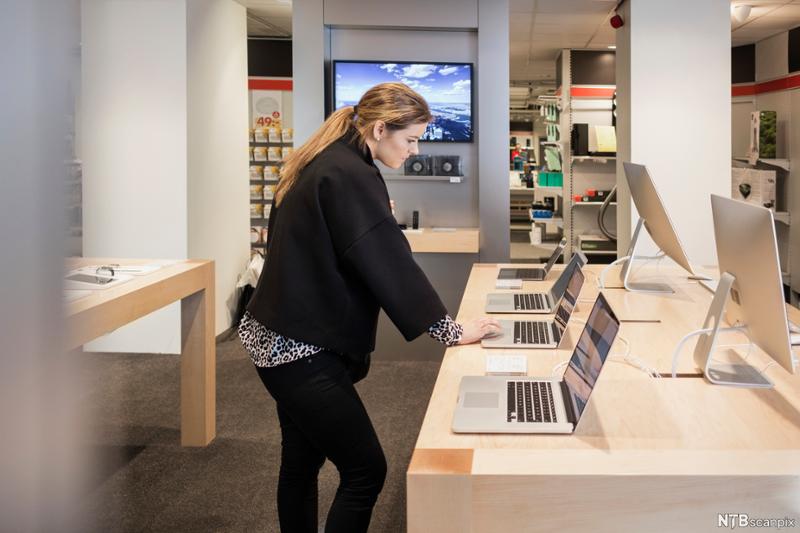 Kvinne ser på mac i butikk. Foto.