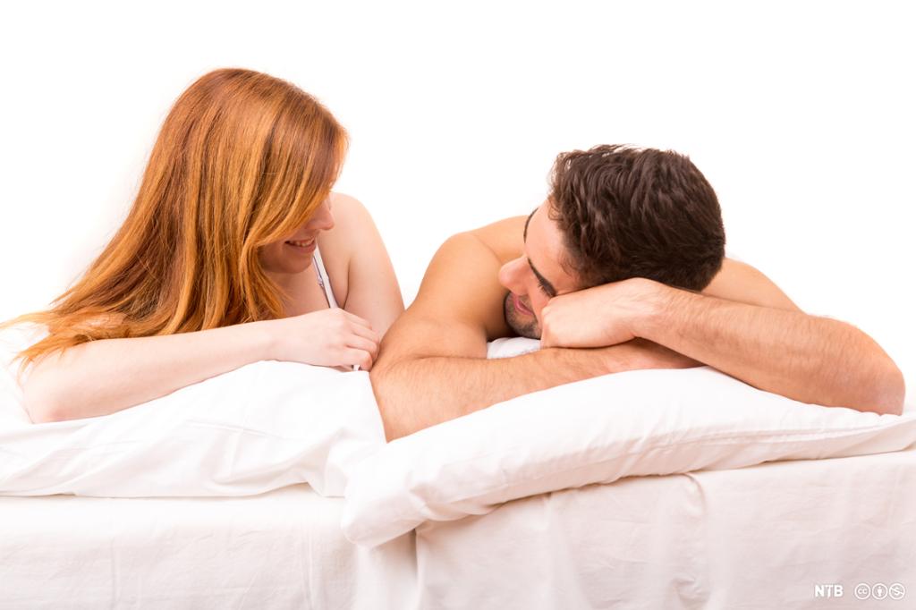 Ei kvinne og ein mann snakkar saman i senga. Foto.