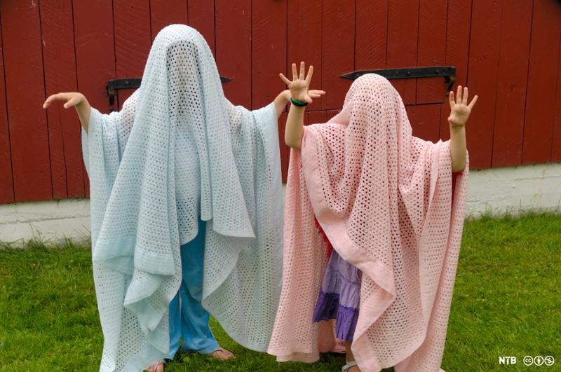 To barn kledd ut som spøkelser med tepper over seg. Foto.