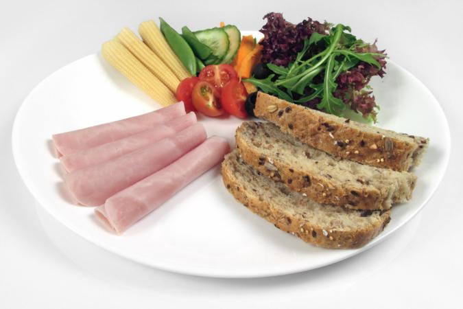 En tallerken med en tredjedel kokt skinke, en tredjedel grovt brød og en tredjedel grønnsaker og salat. Foto.