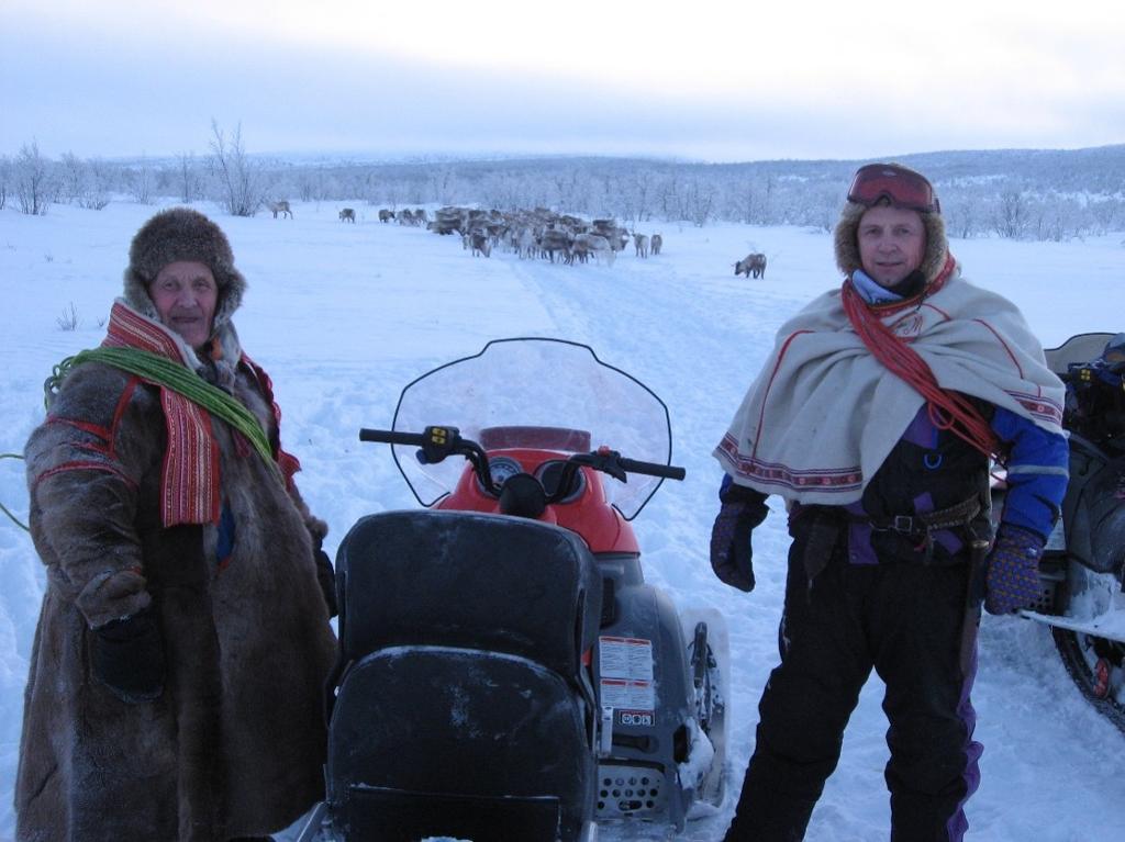 To reingjetarar med snøskuter gjeter flokken. Foto.