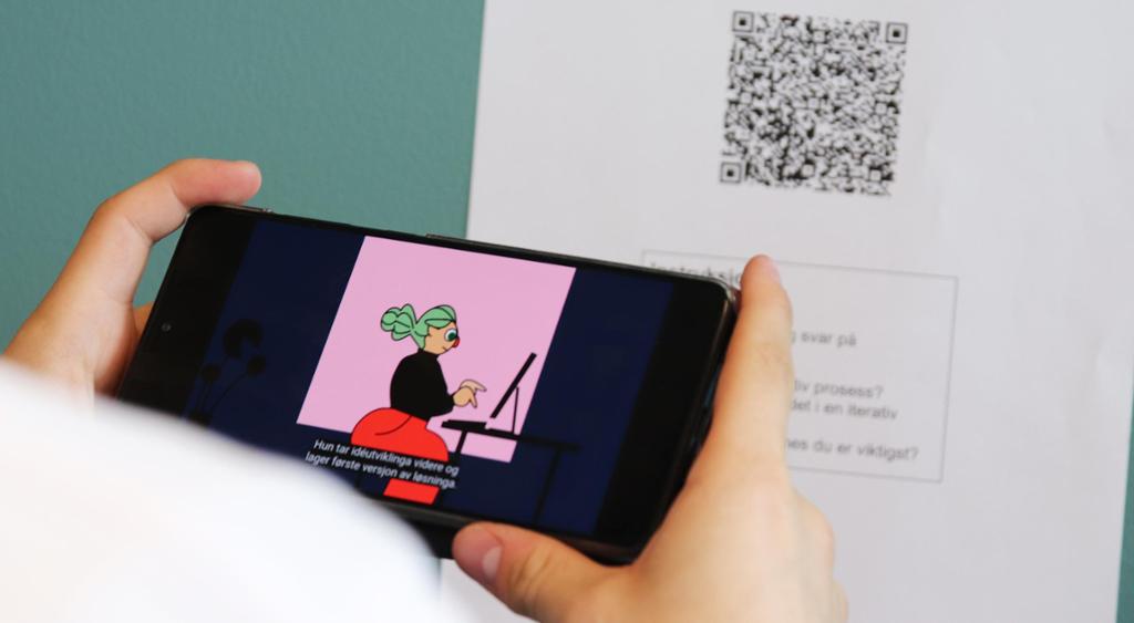 Person ser video og holder opp mobil foran ark med QR-kode. Foto.
