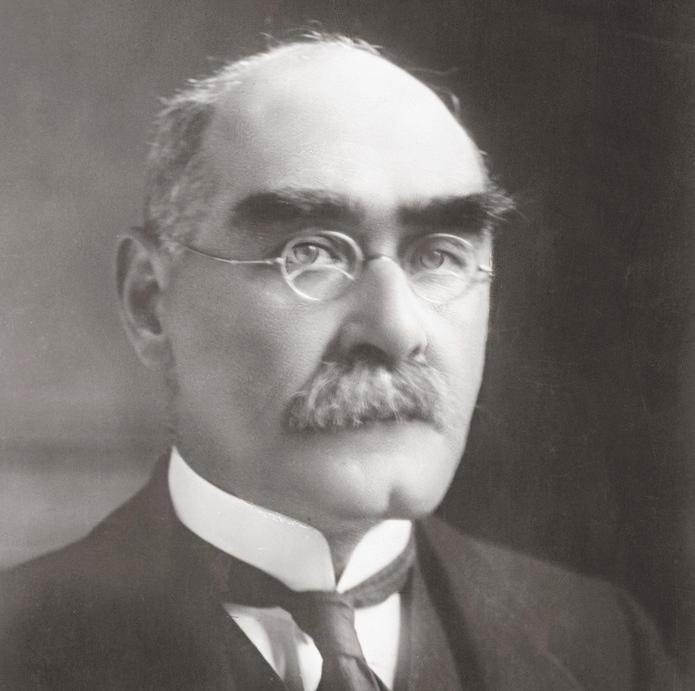 Photo: British author Rudyard Kipling. We see an older, balding man with dark, bushy eyebrows. He has round, wire-framed glasses. He is wearing a suit and tie. 