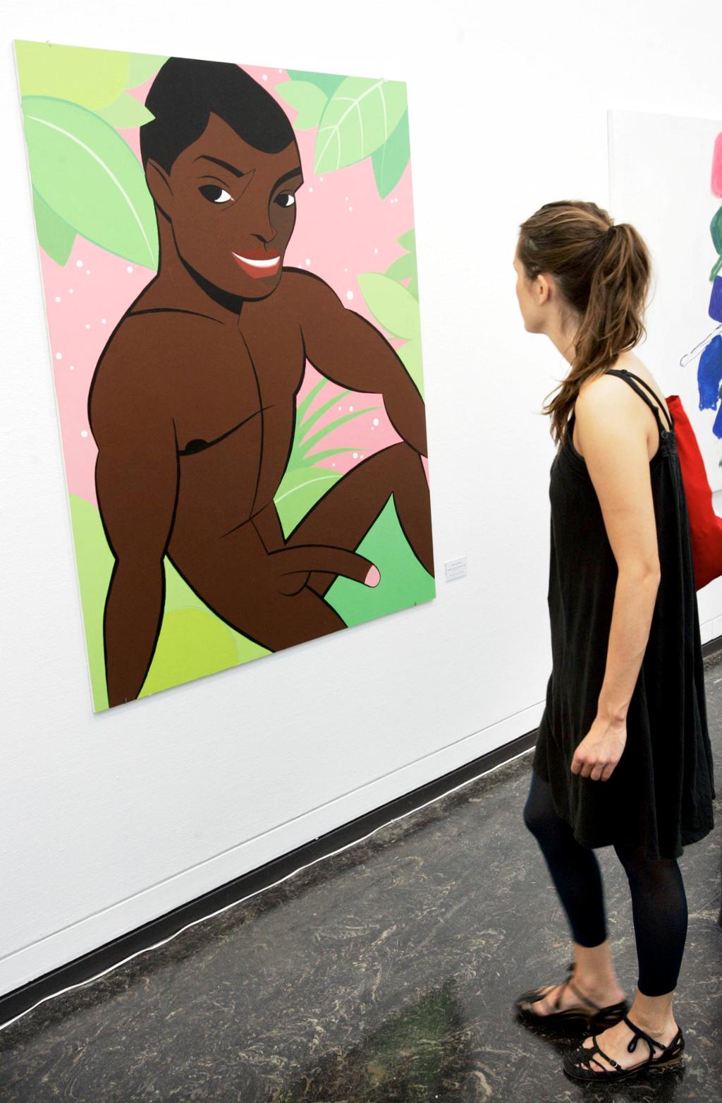 Kvinne ser på et maleri der en mørkhudet mann er framstilt naken med erigert penis. Foto.