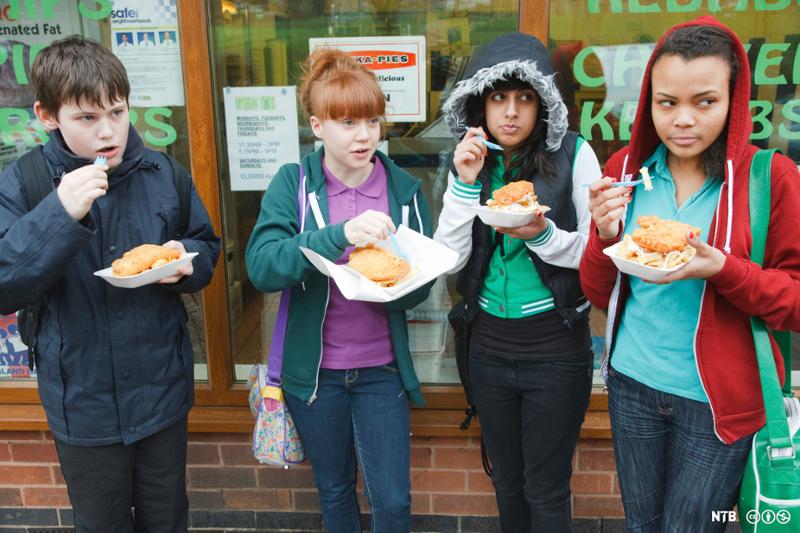 Fire tenåringer spiser fastfood utendørs. Foto.