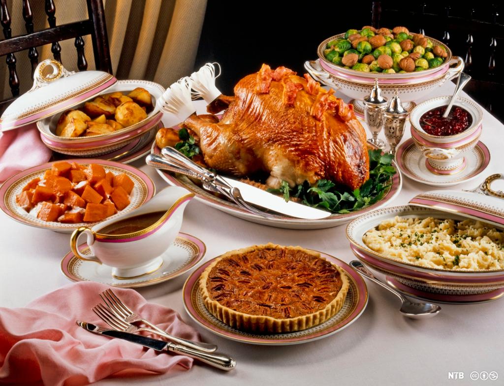 Eit bord med tradisjonelle rettar som blir serverte til thanksgiving: heilsteikt kalkun, potetmos, graskarpai, tranebærsaus, rosenkål og søtpoteter. Foto.