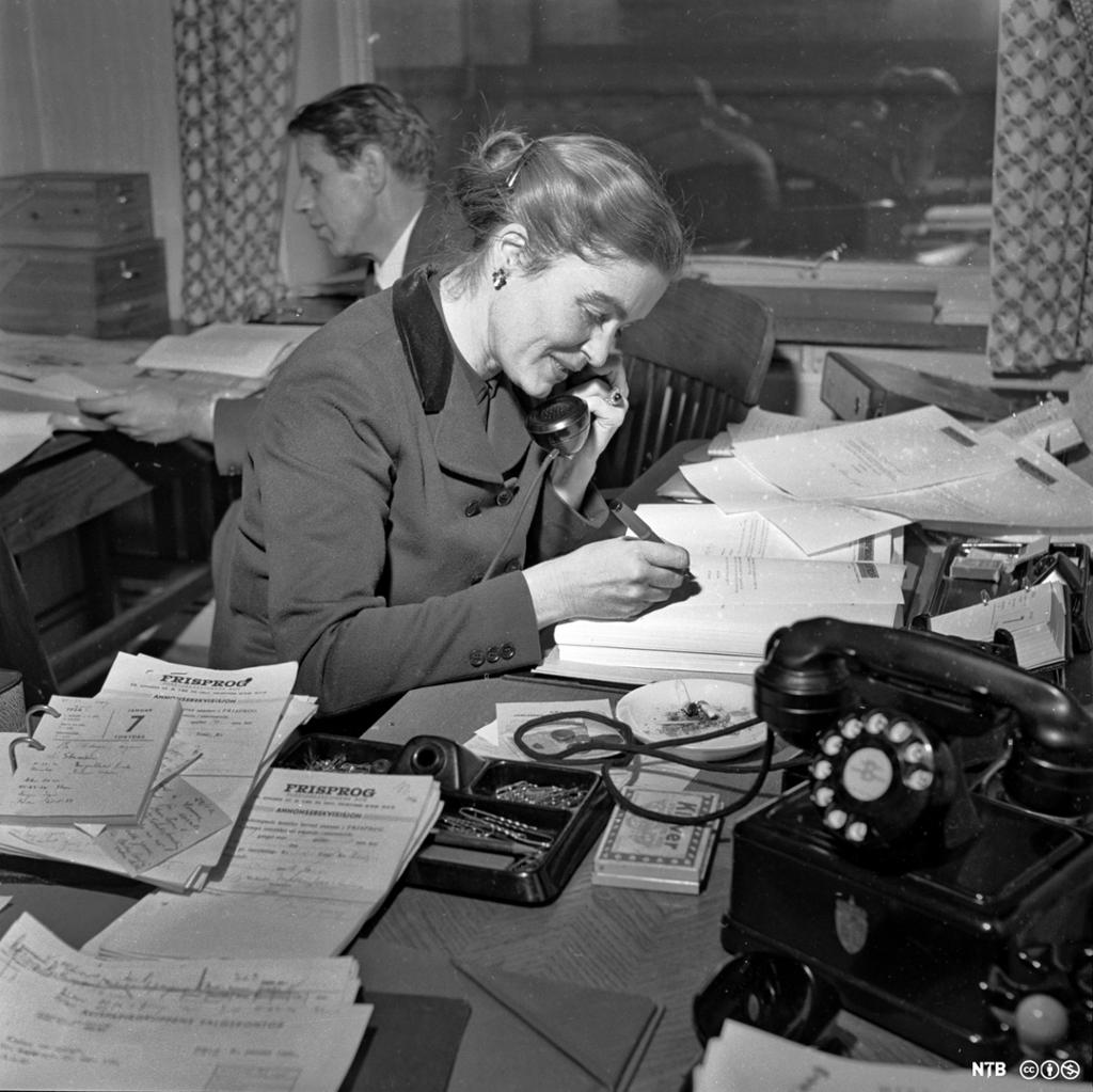 Kvinnelig representant for Foreldreaksjonen mot samnorsk tar imot telefonhenvendelser mens hun skriver på et ark. Foto.