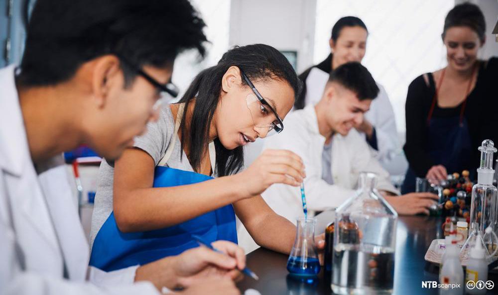 Ungdommar jobbar med kjemikaliar på laboratorium. Foto.
