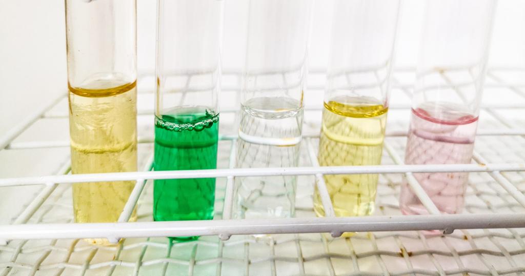 Fem reagensglass med fargede løsninger. Foto.