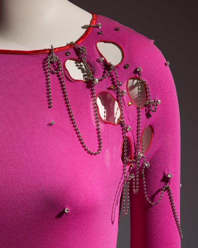 Antrekk designet av Zandra Rhodes i rosa jersey med hull og store sikkerhetsnåler pyntet med perler. Foto.