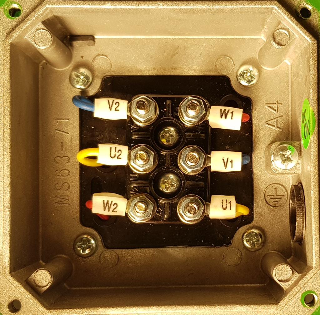 Koblingsboks på en trefaset asynkronmotor. Vi ser ledninger som er koblet til skruer i boksen. Foto.