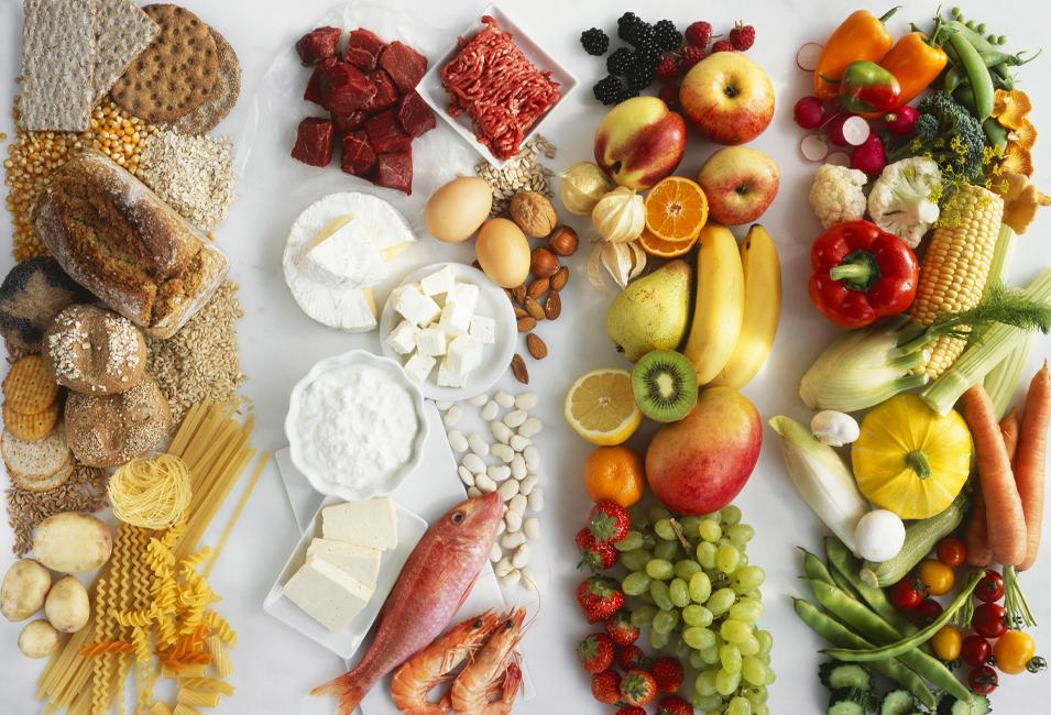 Foto av ulike råvarer som grønnsaker, bær, frukt, fisk, kjøtt, egg og korn- og melkeprodukter lagt utover et bord.