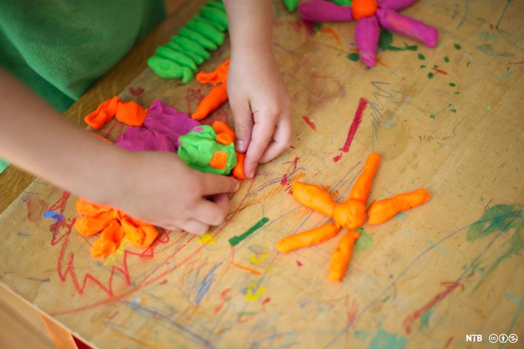 Nærbilde av hendene til jente som leker med plastilin. Foto.
