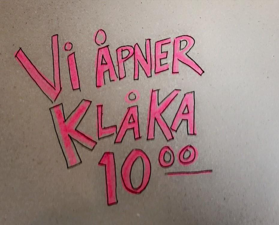 Håndskrevet plakat med teksten "Vi åpner klåka 10". Foto.
