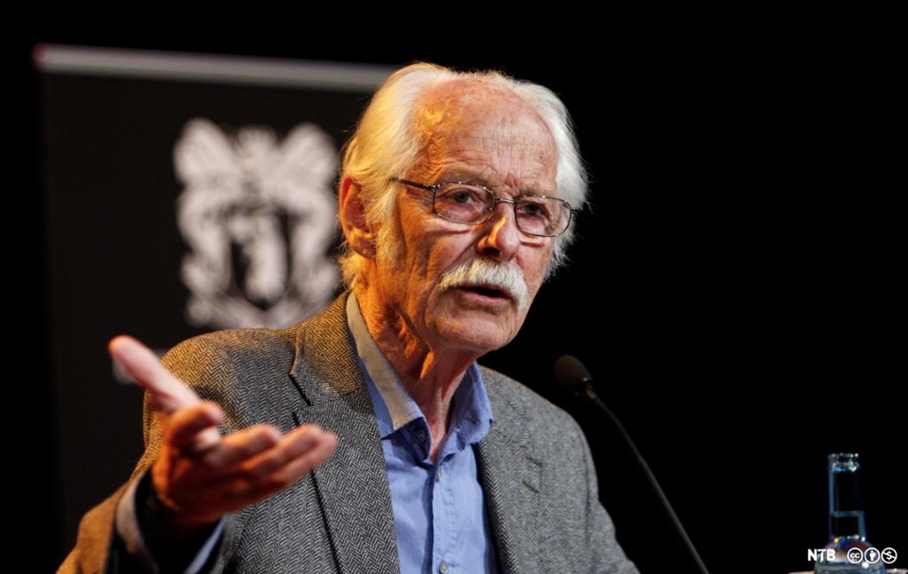 En eldre mann med skjorte og dressjakke gestikulerer. Professor Fredrik Barth innleder i en debatt i 2009. Foto. 