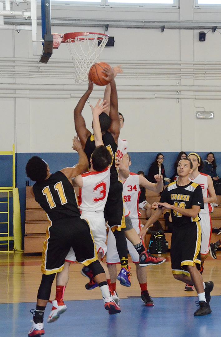 Basketball players in action. One player is about to score a goal, while other players are trying to stop him.