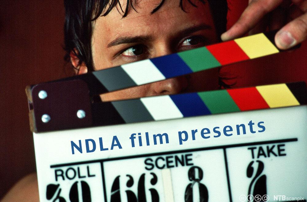 Bilde av en mann som holder et klappbrett. På klappbrettet står det: NDLA film presents. 