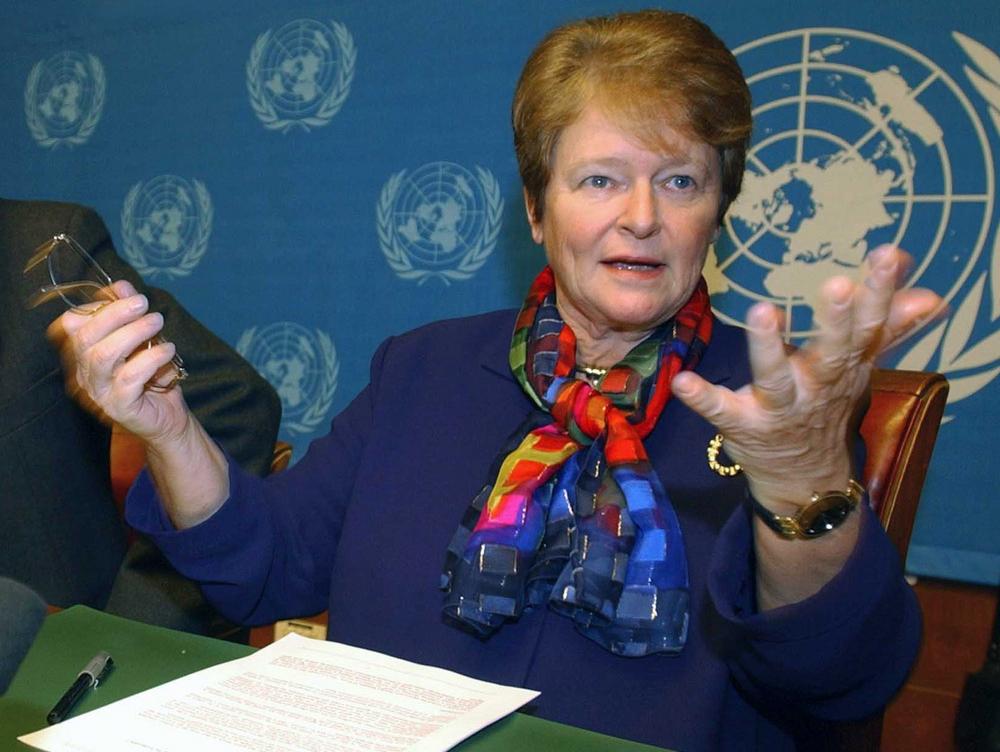Gro Harlem Brundtland snakker. FNs flagg i bakgrunnen. Foto.