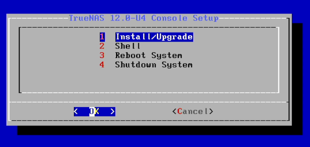 Semi-grafisk installasjonsmeny med fire valg: 1 Install/Upgrade, 2 Shell, 3 Reboot System, 4 Shutdown System. 1 Install/Upgrade er valgt. Skjermbilde.