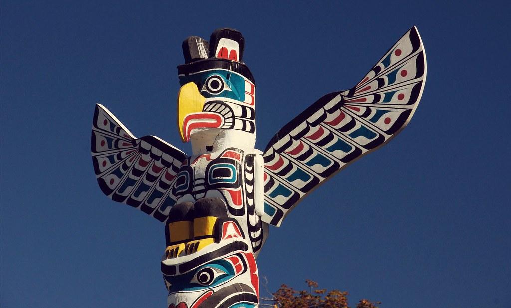 The top of a colourful First Nation totem pole, formed as an eagle. Photo.  