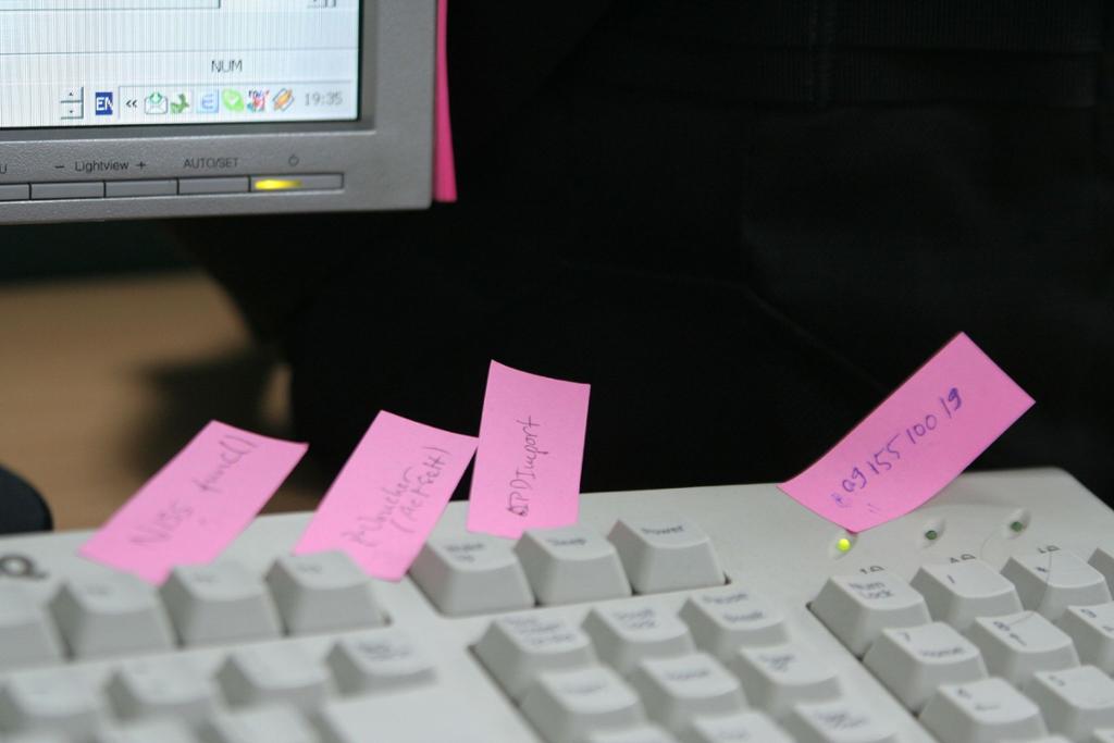På toppen av et tastatur er det klistret små, rosa lapper med tekst og tall på. Foto.