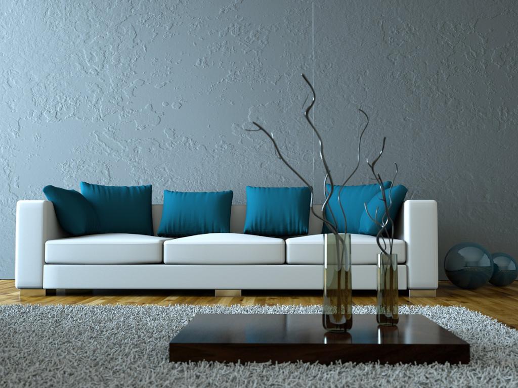 Bordplate med vaser og en hvit sofa med blå puter i et gråblått rom. Foto.