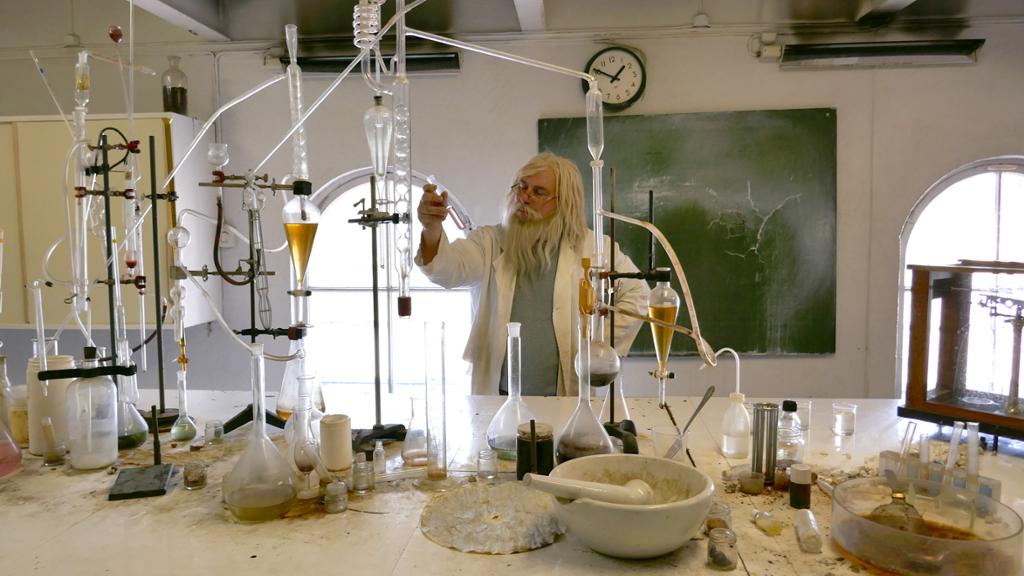En skjeggete mann på et rotete laboratorium. Foto.