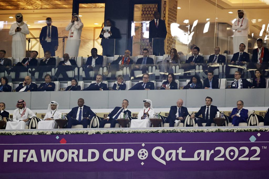 Vestleg kledde og arabisk-kledde tilskodarar på ein tribune. Under tribunen står eit skilt med Fifa World cup Qatar 2022. Foto.