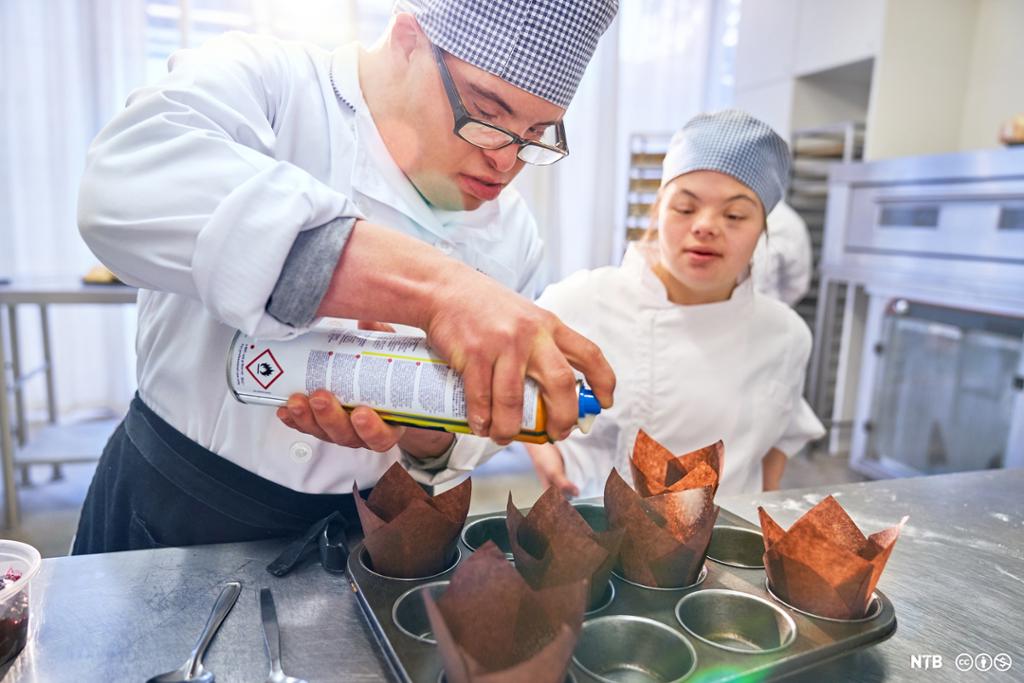 To studenter med Downs syndrom baker muffins på kjøkkenet. Foto.