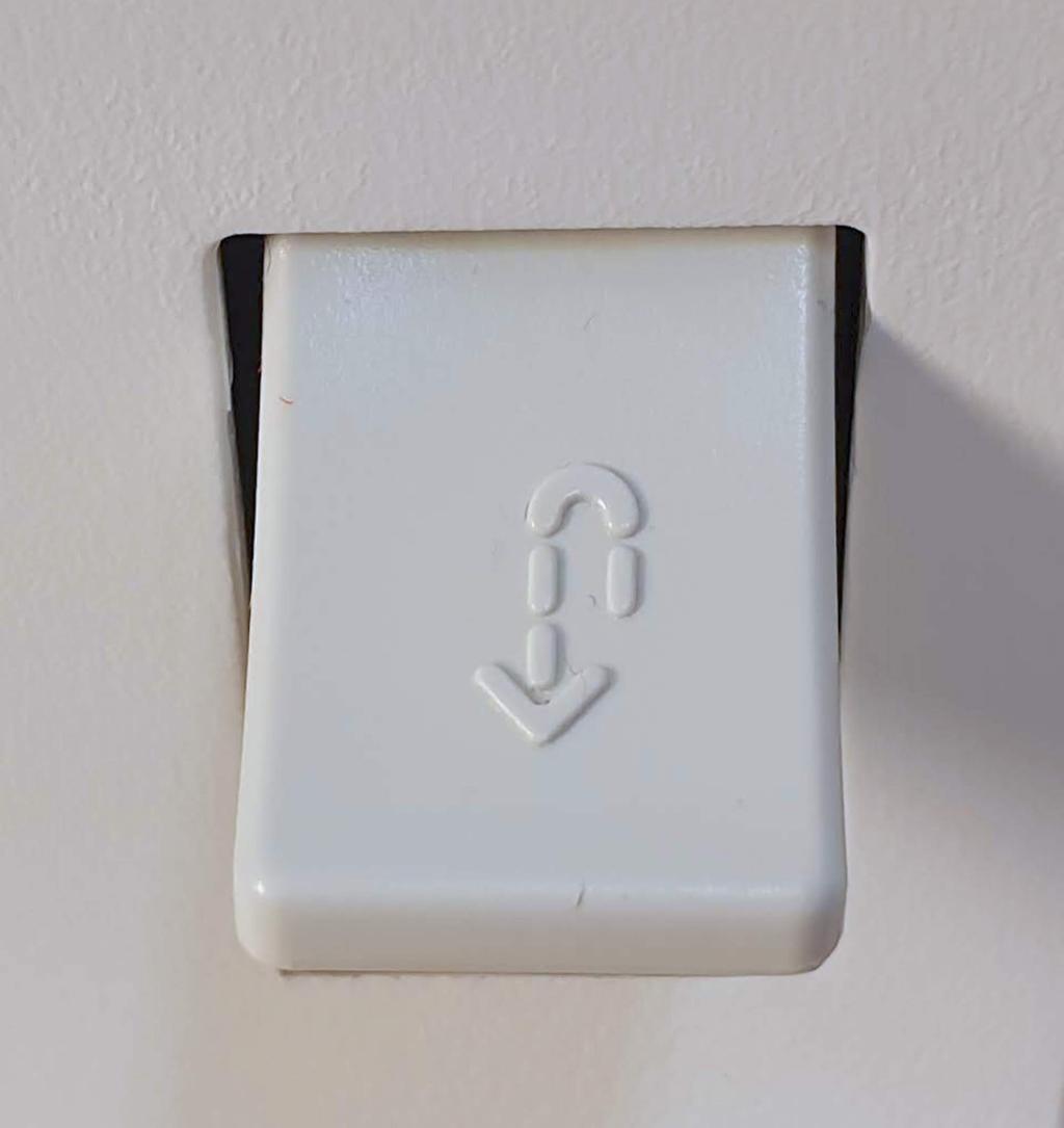 Fotografi av hvit knapp med en stiplet pil som snur og går tilbake.