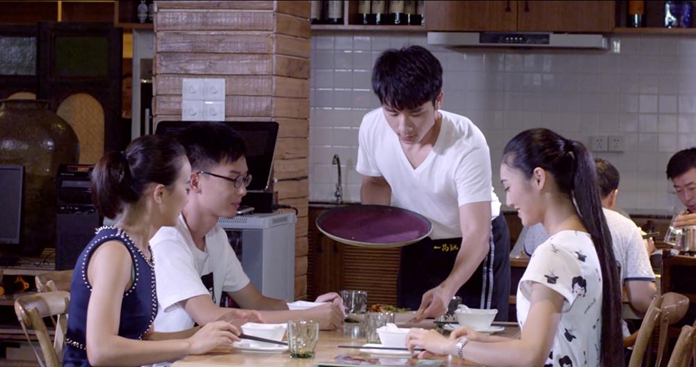 Tre unge kinesere blir servert mat på restaurant. Foto.