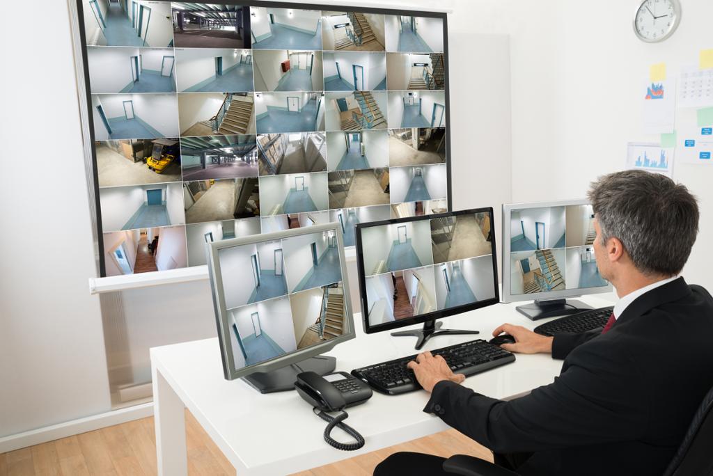 Mann i kontrollrom overvåker flere cctv-opptak. Foto.