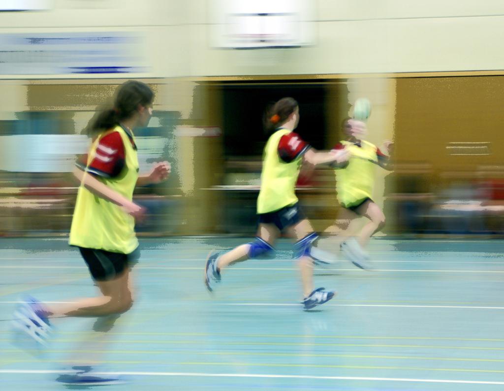 Håndballspillere i gymsal. Bevegelsesuskarpt. Foto.