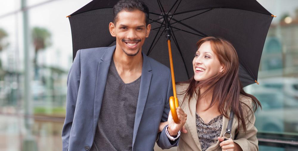 Mann og dame deler paraply. Foto. 