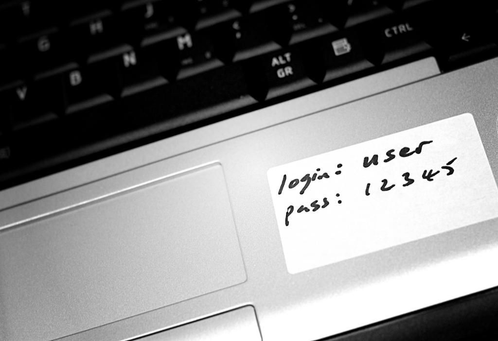 Brukarnamn og passord skrive på ein lapp på ein berbar datamaskin. Foto.