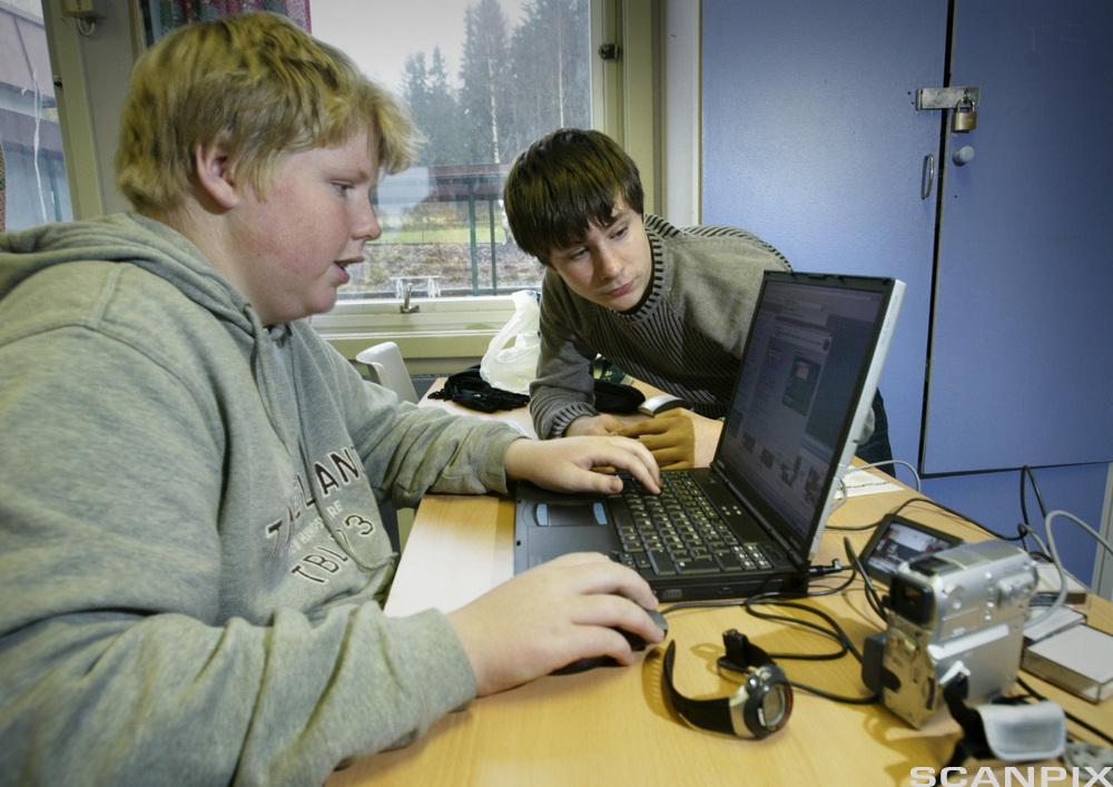 En gutt jobber med pc, en annen ser på.